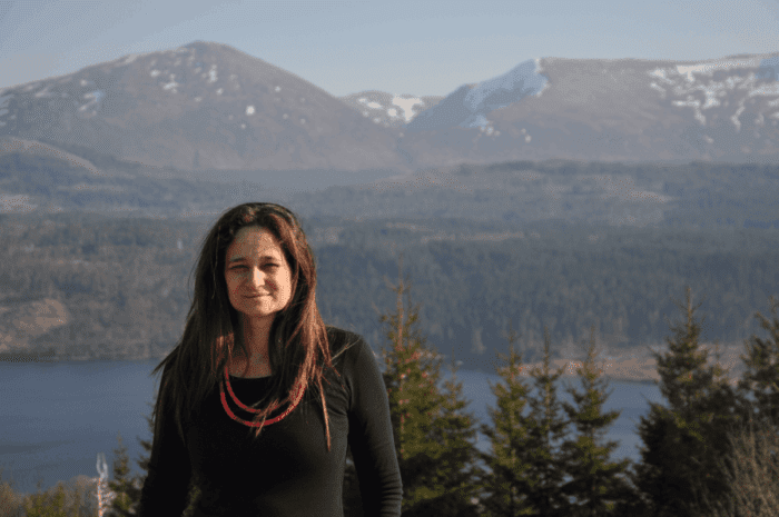 Foto da professora e bióloga Deborah Faria em cenário com montanhas e árvores ao fundo